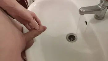 Gay with a shaved cock pissing in the sink